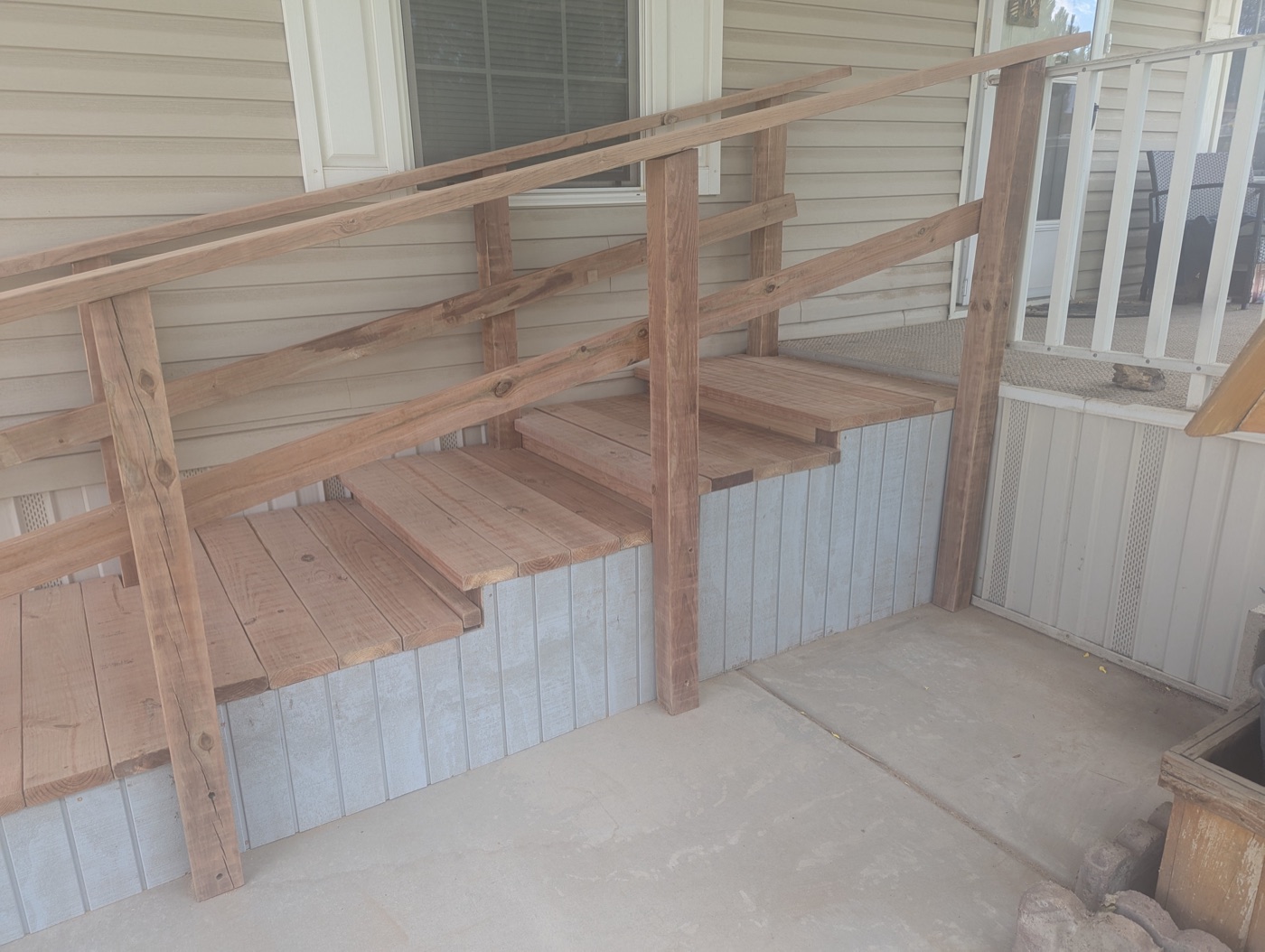 Close-up of wide-tread access stairs showing 4x4 posts, double handrails, and metal skirt panels