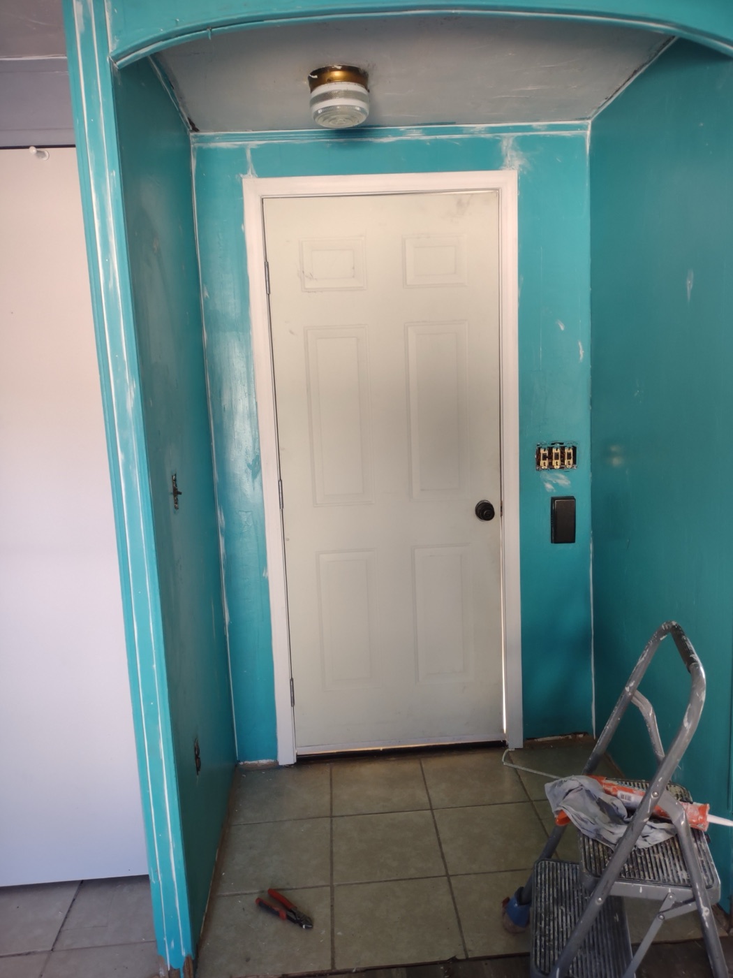 Entryway being repainted teal with electrical switch box mid-install over tile floor