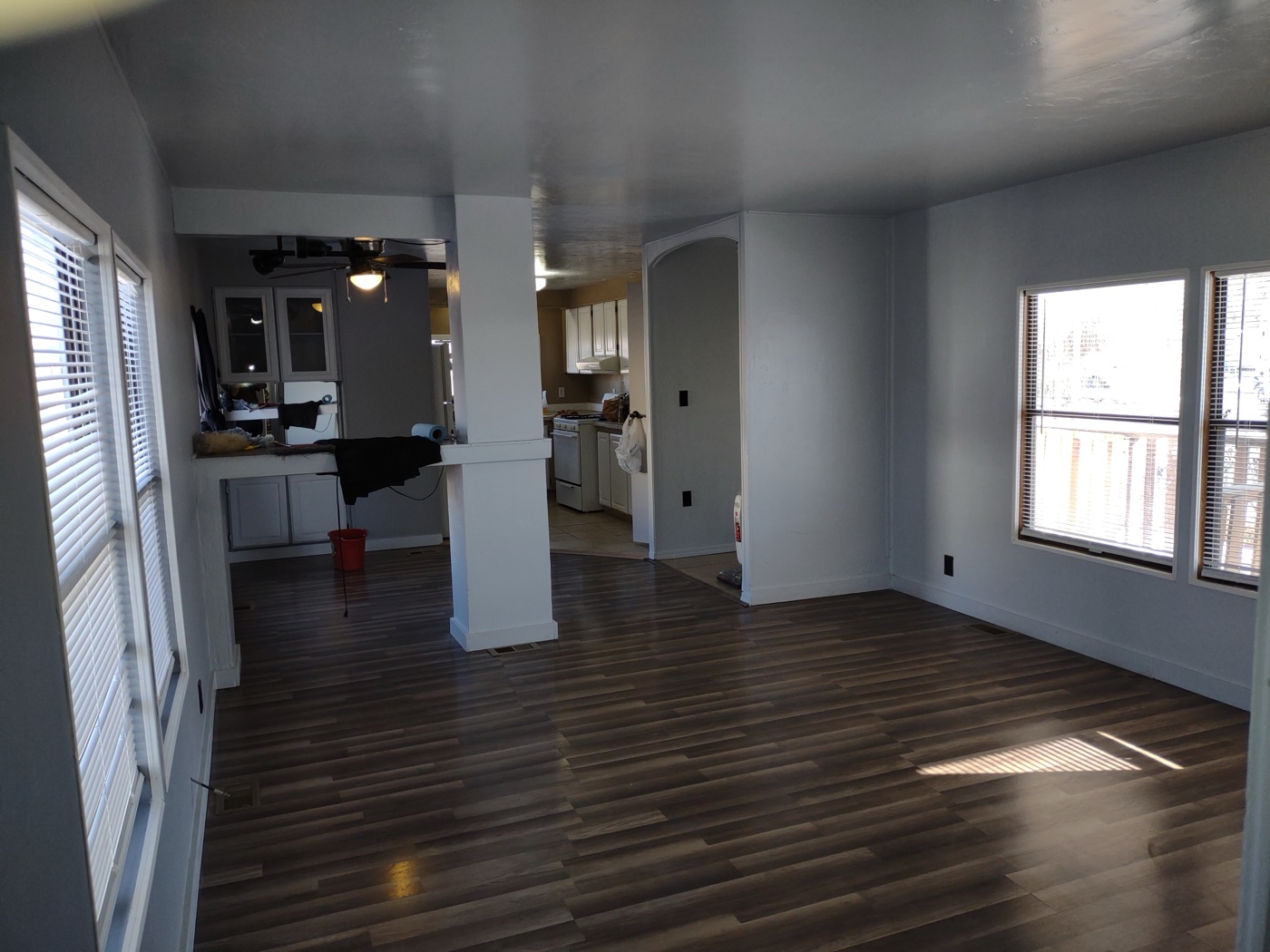 Open living and kitchen space with new dark LVP flooring throughout and fresh gray walls